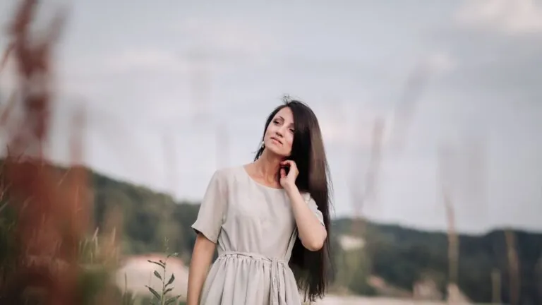 Woman with long dark hair standing outdoors on a summer day