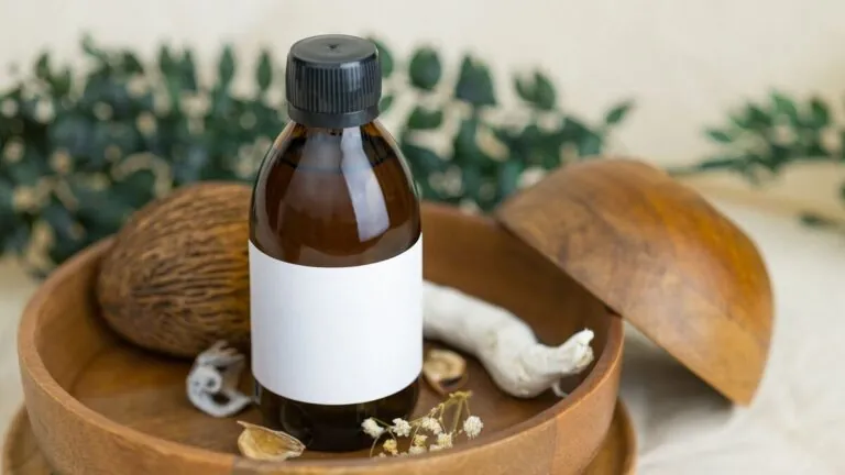 Amber oil bottle in a wooden bowl with herbs