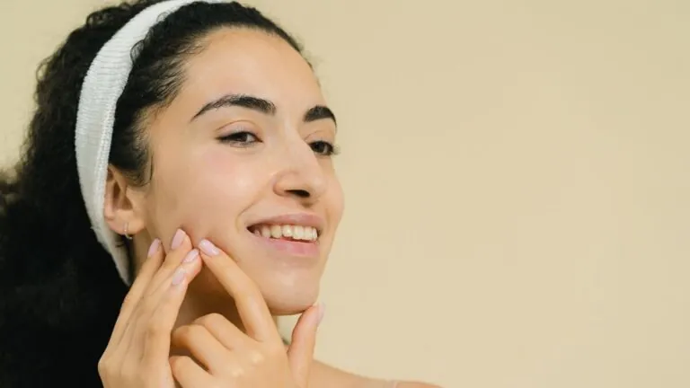 Smiling woman with headband touching her glowing cheek