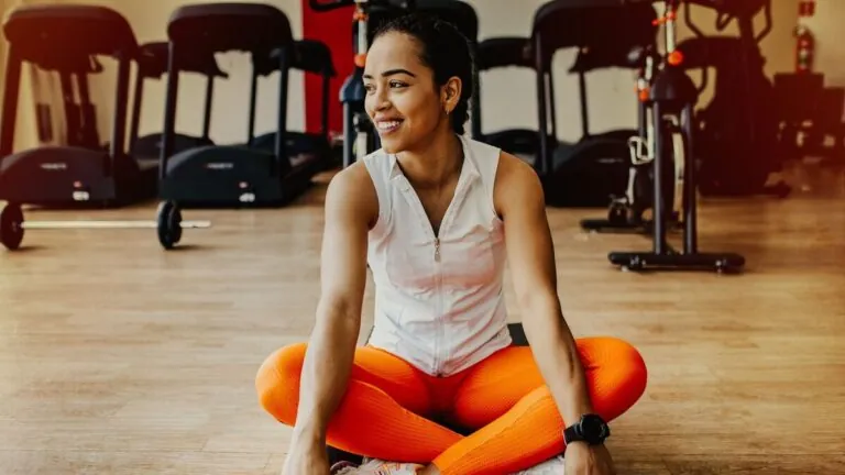 Smiling woman sitting cross-legged on a gym floor