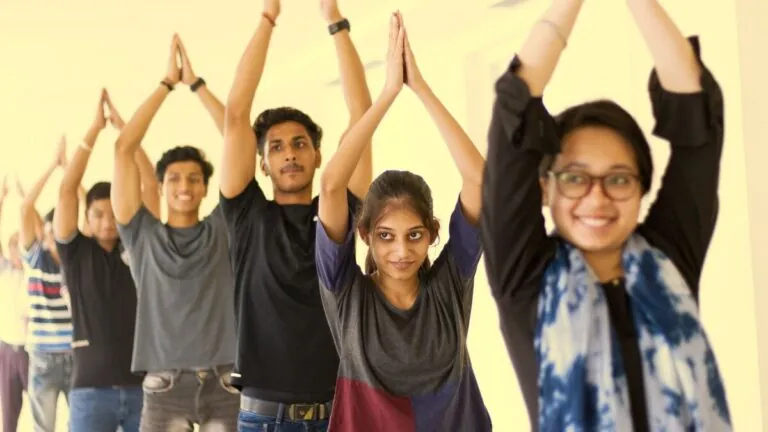 Young Indian students doing yoga with arms raised overhead