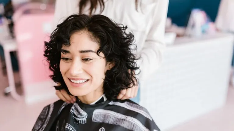Smiling woman with curly hair at a hair salon