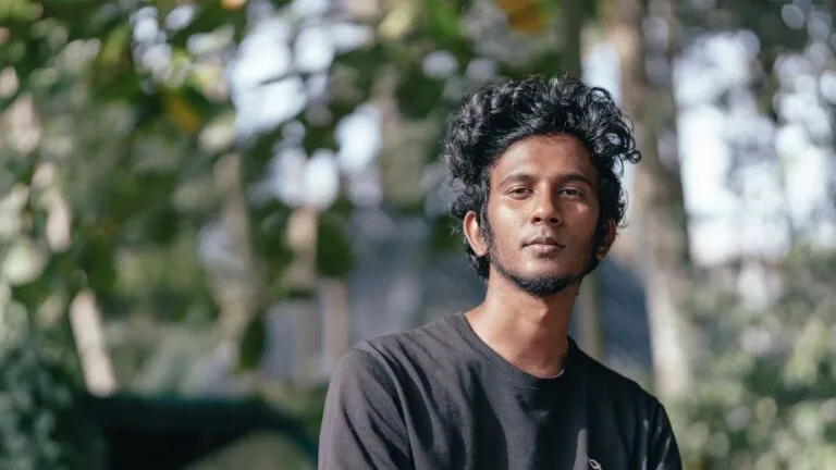 Young Indian man with dark curly hair outdoors