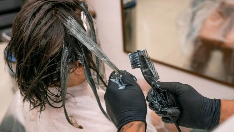Stylist brushing hair colour onto a woman's hair at a salon