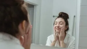 Woman washing her face, reflected in a bathroom mirror