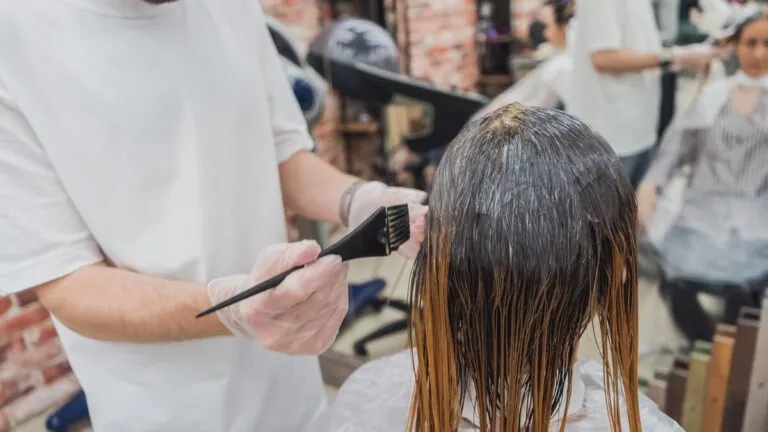 Hairdresser applying hair colour with a brush in a salon