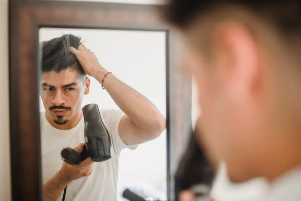 Man styling his hair in front of a mirror