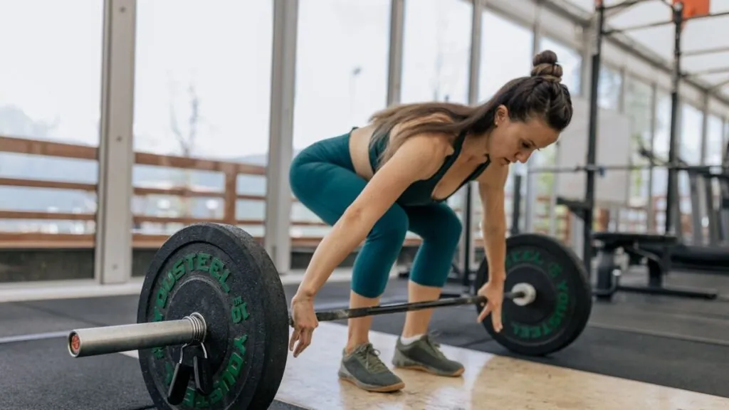 Woman lifting a loaded barbell in a bright gym