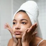 Woman in a hair towel washing her face