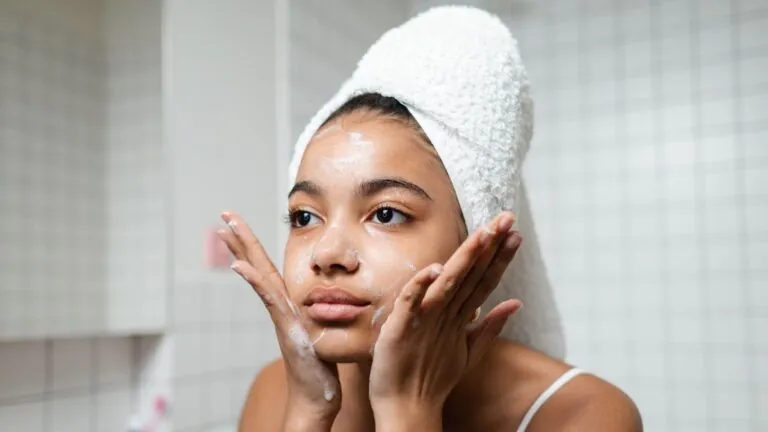 Woman in a hair towel washing her face
