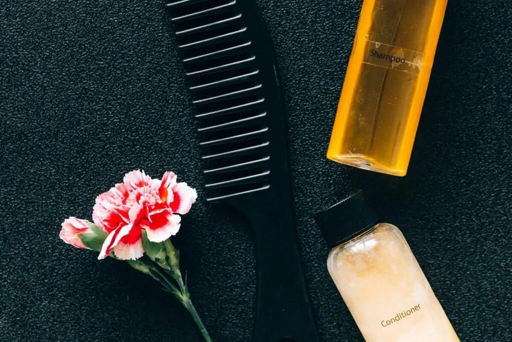 Hair care bottles and a wide-tooth comb on a dark surface