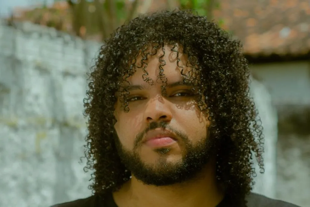 Man with curly hair and a beard outdoors