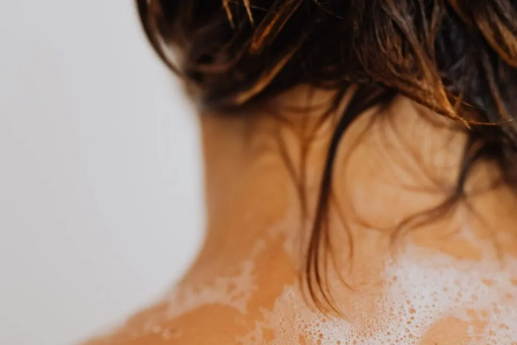 Wet hair with shampoo lather on the shoulders