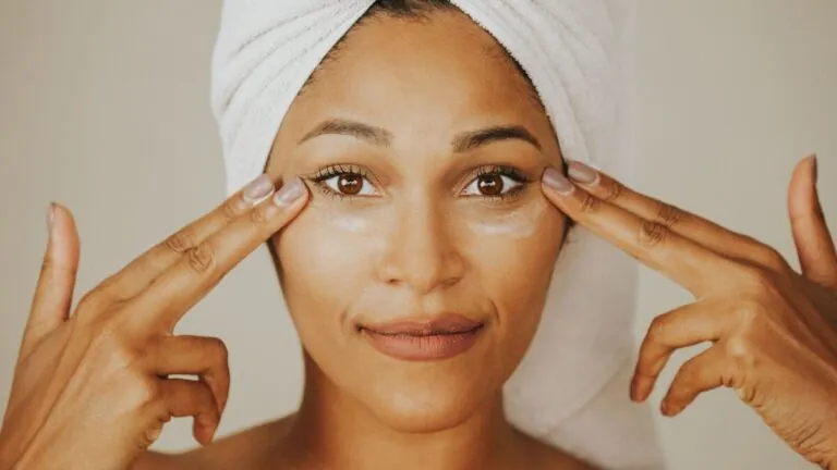 Woman in a towel wrap tapping under eye cream along her under-eye area