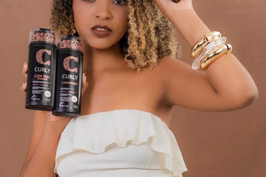 Woman with curly hair holding curl care products