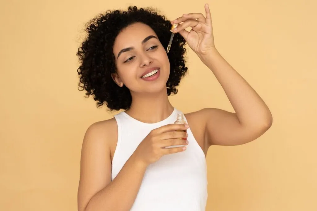 Woman with curly hair applying a few drops of hair oil