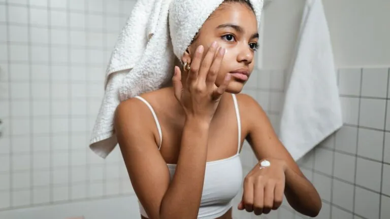 Woman in a towel wrap applying moisturiser to repair her skin barrier