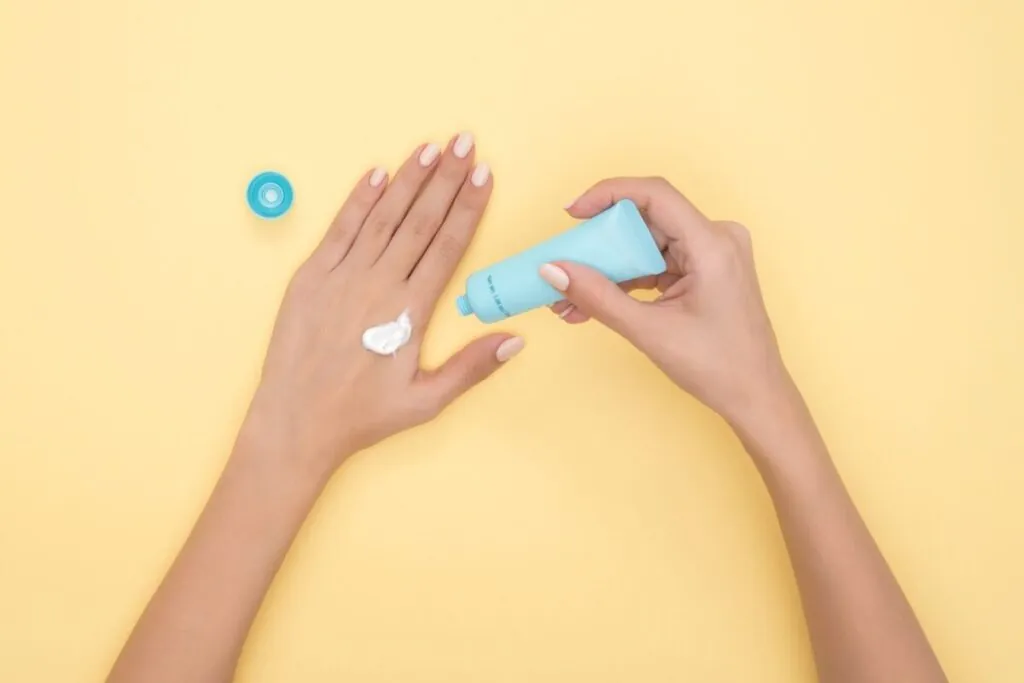 Hands squeezing sunscreen onto a fingertip