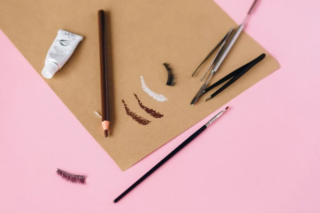 Brow pencils, tweezers and eyebrow swatches on kraft paper