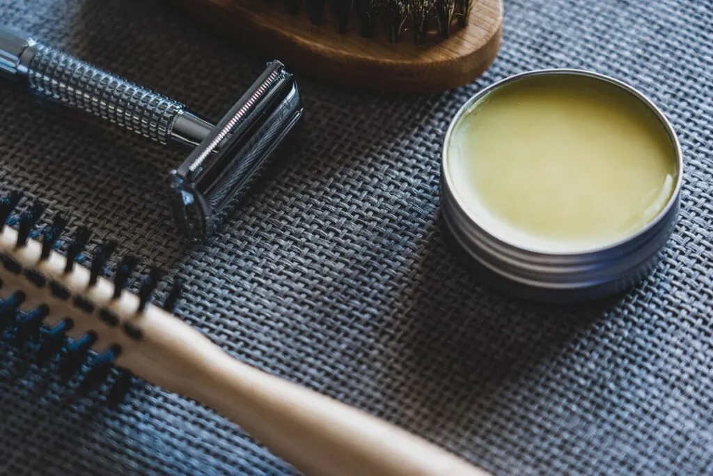 Grooming tools and an open tin of hair wax on a blue cloth