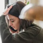 Worried woman holding her head and touching her hair