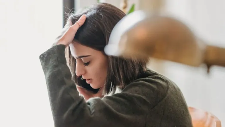 Worried woman holding her head and touching her hair