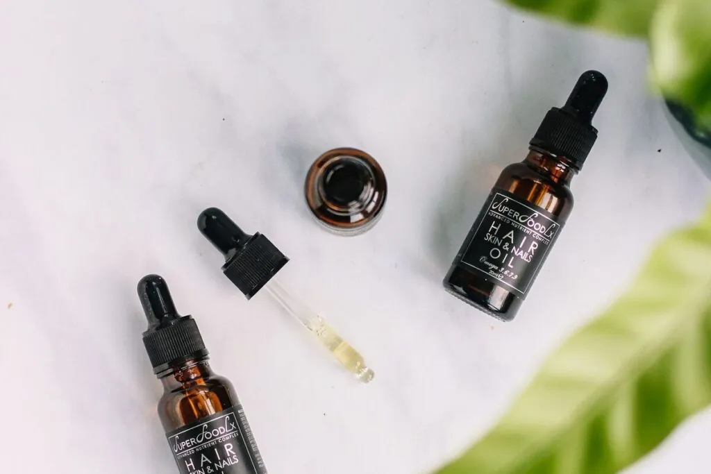 Hair oil bottles with dropper caps and green leaves