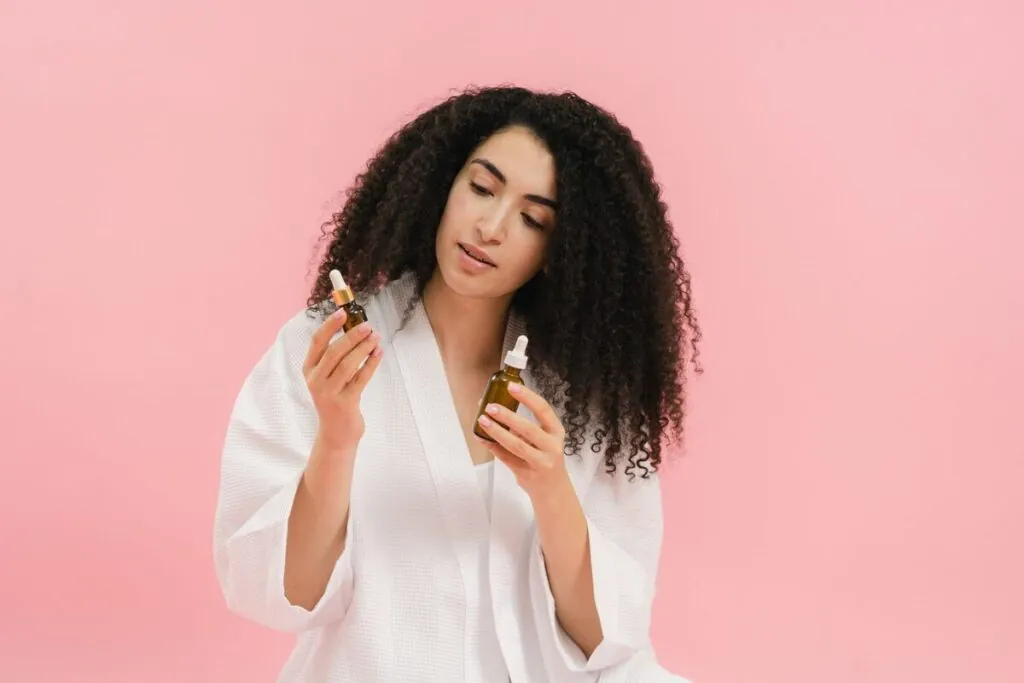 Woman with curly hair holding a bottle of hair oil