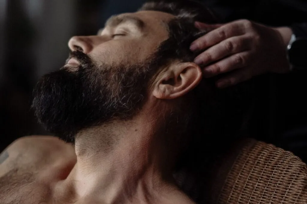 Bearded man massaging his scalp with his fingertips