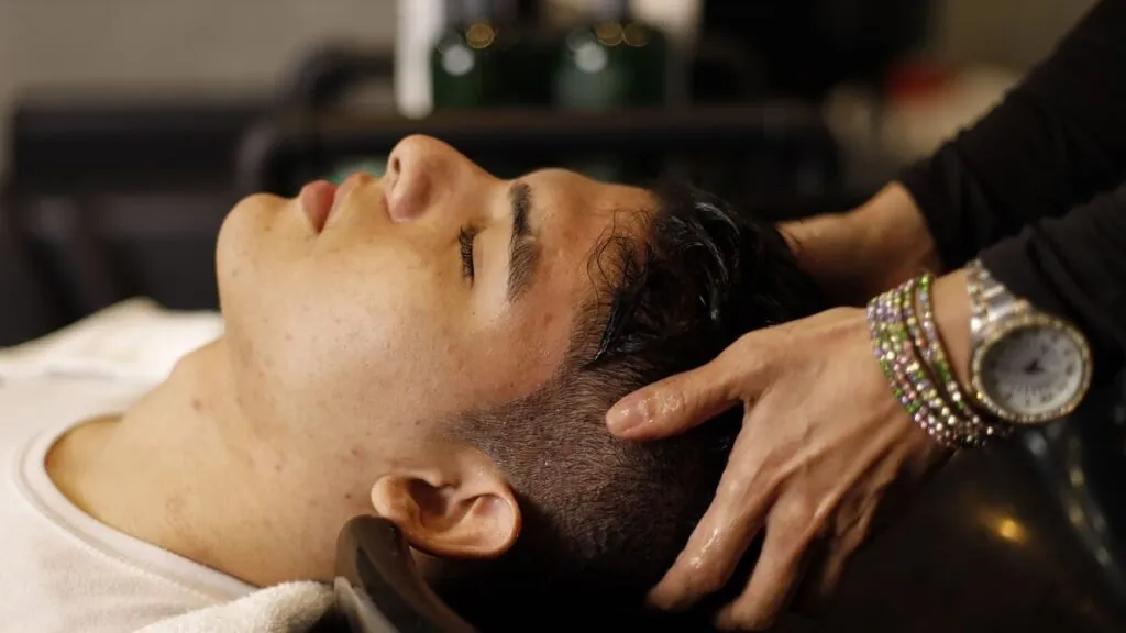 Man lying back at a salon basin getting a scalp massage