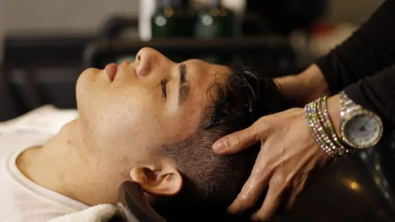 Man lying back at a salon basin getting a scalp massage