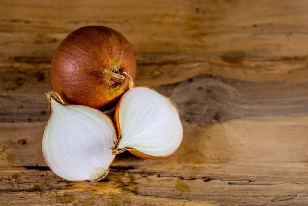 Whole and sliced onion on a wooden table