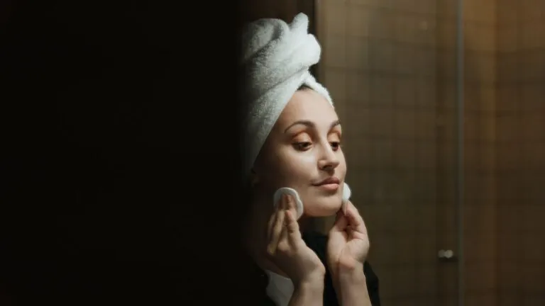 Woman cleansing her face with a cotton pad during a night skincare routine